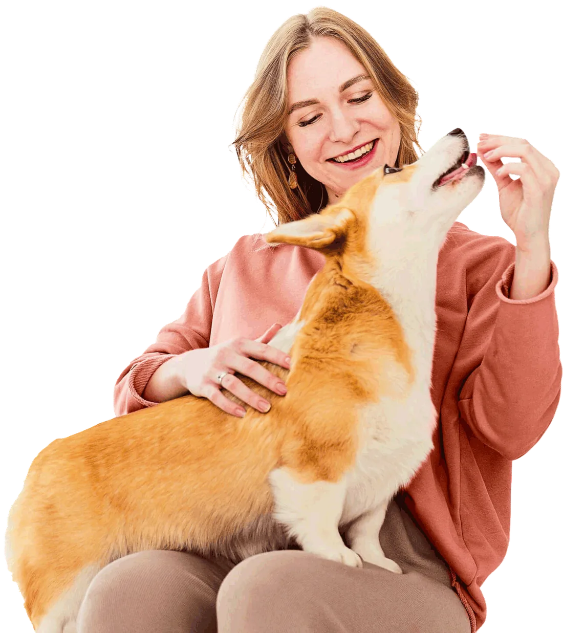 Tutora sorrindo enquanto dá um petisco a um corgi